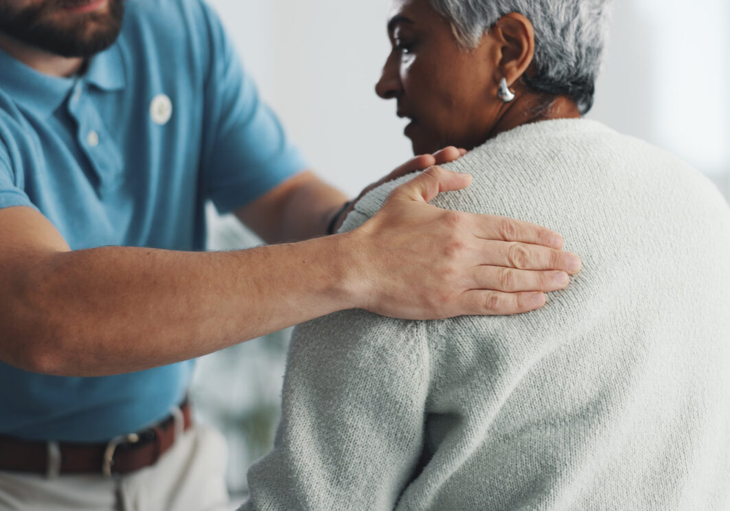 Old woman, shoulder pain and physiotherapy with man in office for consulting, health and rehabilitation. Muscle recovery, medical and support with senior patient for physical therapy and advice
